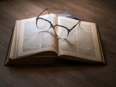 An open book with glasses resting on the page