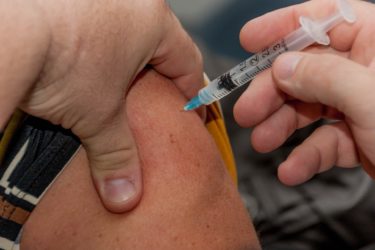 A person has a vaccination administered into their upper arm