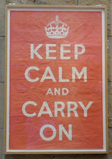 A red poster with white writing that reads "Keep Calm and Carry On"