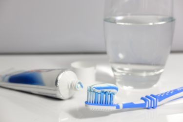 A toothbrush, toothpaste and glass of water