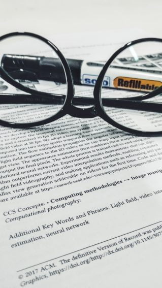 An academic paper with a pair of glasses resting on top. 