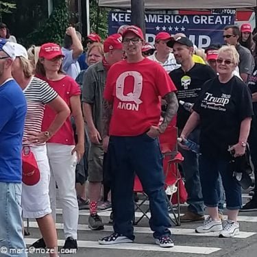 Man standing in a group of people who are wearing Trump 2020 paraphernalia - the man is wearing a red QAnon t shirt. [CC 2.0]