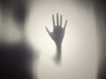 A shadowy figure holding their palm out