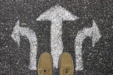 A person stands at three directional arrows drawn with chalk on the floor.