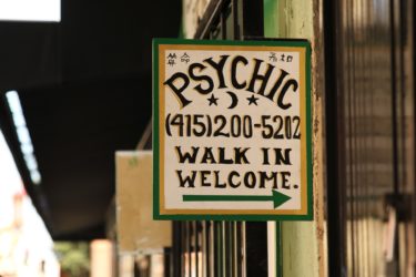 Advert for a Psychic that reads "Psychic" a phone number and the words "walk in welcome" with an arrow.