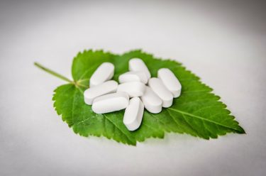 White tablets sitting on top of a nettle leaf