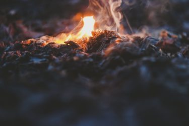 A smouldering fire nearing the end of its life leaving a pile of ash