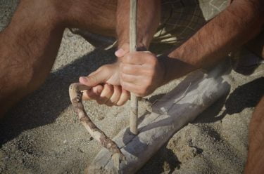 A person making fire with sticks