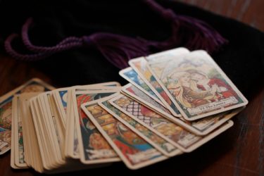 Tarot cards on a table next to a dark purple velvet bag