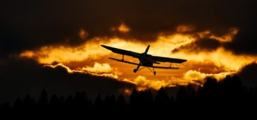 A plane flying into a sunset