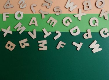 Wooden cut out letters on a green and orange background