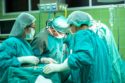 A surgical team standing over a patient