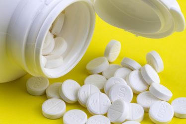 white tablets spilling out of a white container