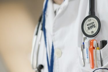 A doctor wearing a lab coat and stethoscope around their neck. 