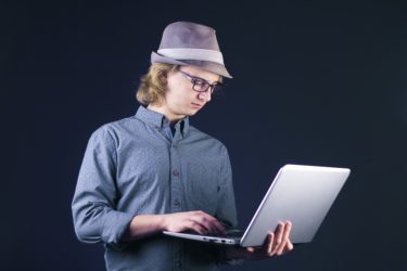 A stereotypical male computer geek in a hat holds a laptop. The stereotype is far from reality, and is often applied only to male individuals. 

Image from https://pixabay.com/photos/laptop-computer-internet-people-3091427/