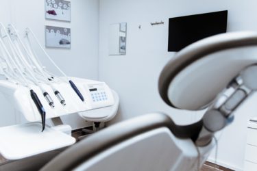 The back of a dentist's chair with dental tools in front.