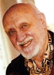 Lewis Jones - an older white man with a bald head and a short white beard and moustache. He is smiling at the camera. 