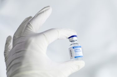 a gloved hand holding a vaccine ampoule