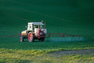 A tractor spraying a field with pesticide