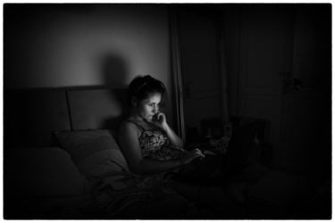 A woman looking at her laptop in a dark room