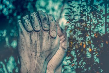 A sculpture of stone hands clasped in prayer.