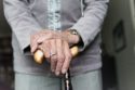 A walking stick in the hands of an older woman.