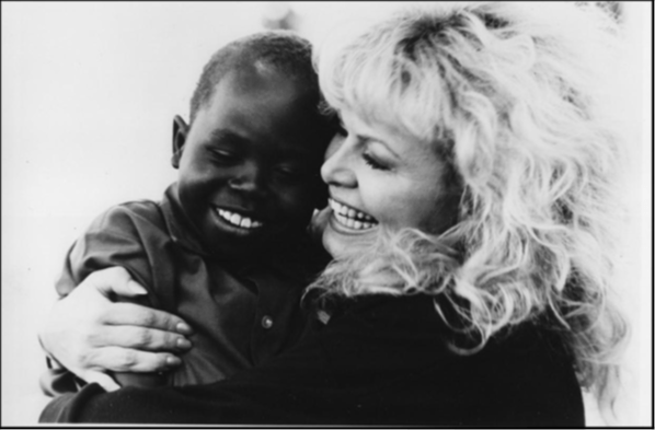 A white woman (Sally Struthers) cuddling a black child