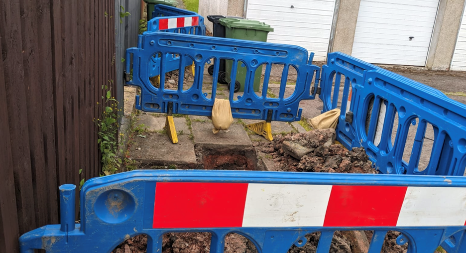 Blue boards surrounding a hole in the paving