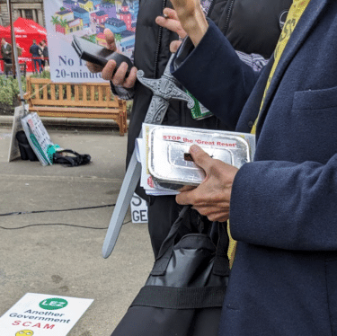 A photograph of two people, one carrying a plastic sword, the other a tin foil covered takeaway container. 

Source: Brian Eggo