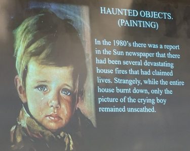 Slide titled "Haunted Objects. (Painting)" with an image of a painting of a crying boy and description, which reads "In the 1980's there was a report in the Sun newspaper that there had been several devastating house fires that had claimed lives. Strangely, while the entire house burnt down, only the picture of the crying boy remained unscathed."
Source: Brian Eggo