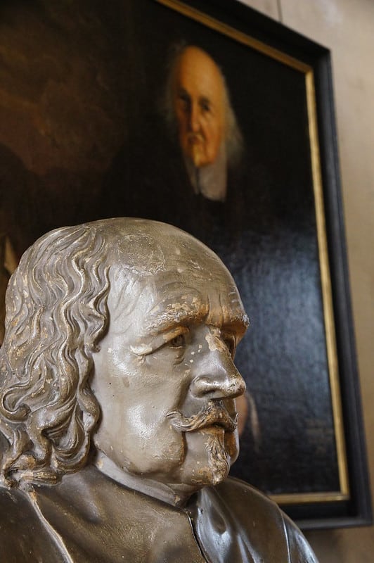 In the foreground is a bust of Thomas Hobbes that sits to the front-left of a portrait of the same man.