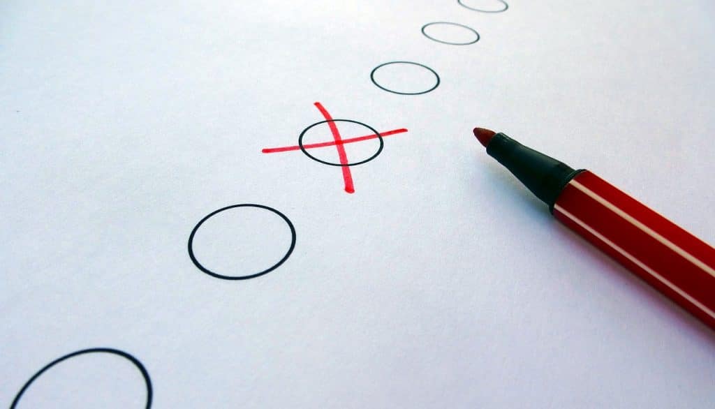 6 empty checkmark circles on paper, with one filled in with a red felt pen cross. The tip of the pen is visible to the right as the pen has been laid down on it.