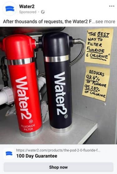 A sponsored Facebook post from Water2, with a link to their site that' slabelled 100 Day Guarantee. In the image, two canisters labelled Water2 'Fluoride Filter' in red and black, installed under a sink. To their right, two Post-It notes with black marker writing saying "THE BEST WAY TO FILTER FLUORIDE & CHLORINE" with 'best', 'fluoride' and 'chlorine' underlined, and "REDUCES 98.4% OF FLUORIDE 95.28% OF CHLORINE", with the percentages underlined.
