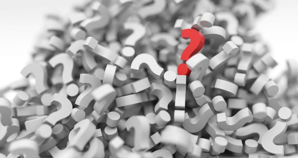 a pile of white question marks in 3D, with one red one upright in the upper right of the image