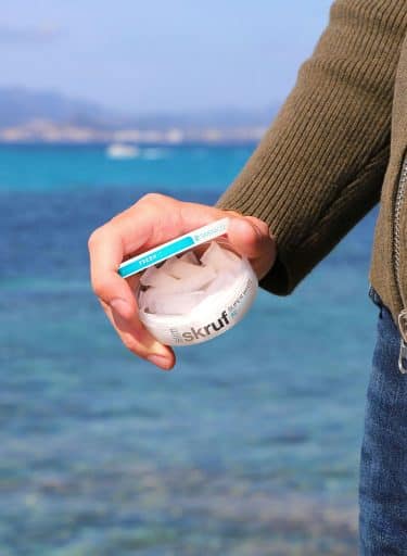 Close up of a man's hand holding a round box containing sous pouches.