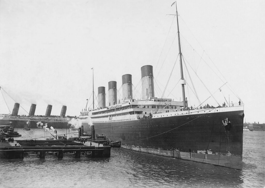 The RMS Olympic in the foreground, a huge Titanic-like ship with four chimneys, leaving port in 1911. A similar ship, the RMS Lusitania is behind it.