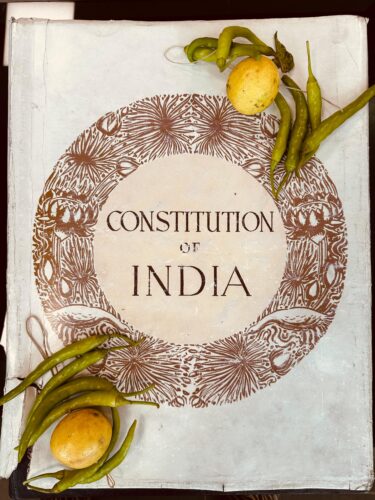 Chilli-and-lemon talismans placed on the top-right and lower-left corners of a copy of the Constitution of India