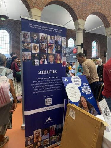 An ADF UK stand for 'amicus', featuring a checkerboard of photographs of people. 