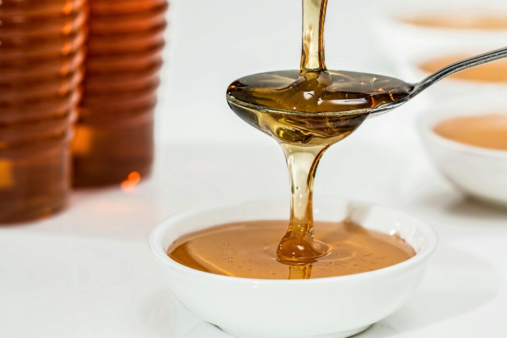 Honey being poured onto a spoon and overflowing into a bowl