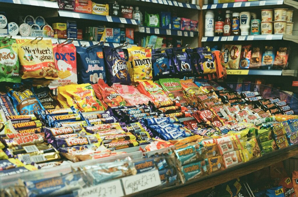 A range of chocolate bars and bags of sweets on sale in a small UK corner shop/convenience store.