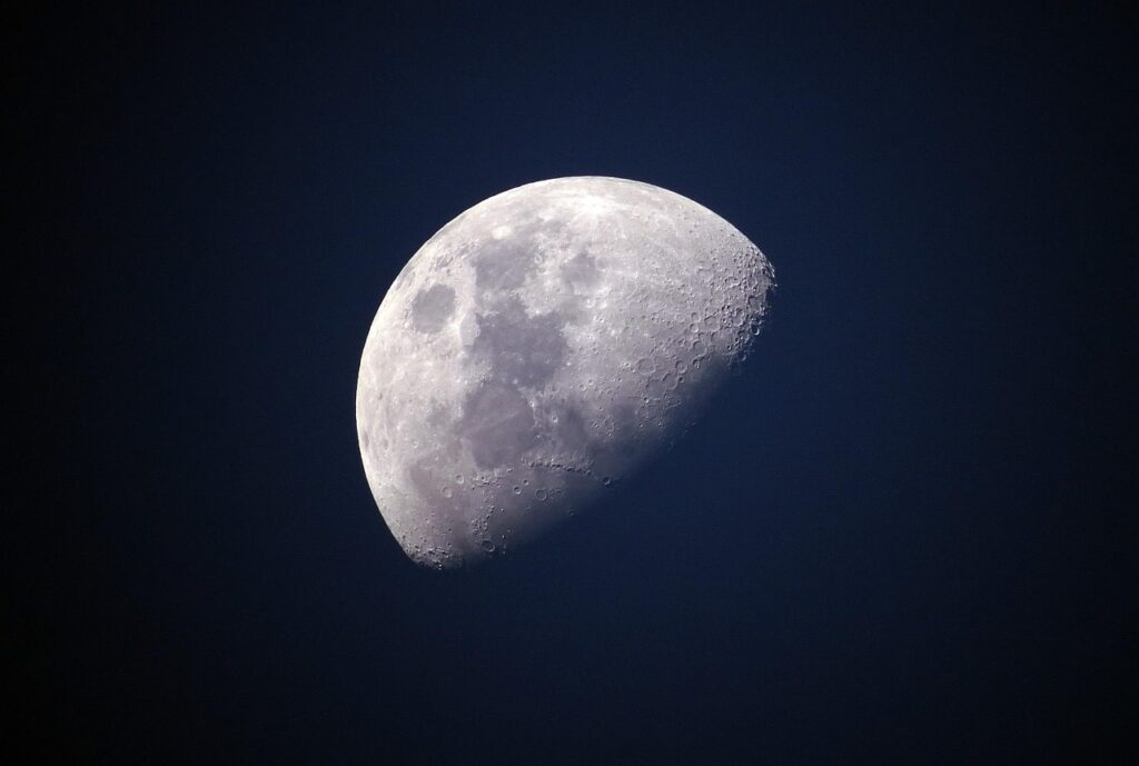 Photograph of a gibbous – slightly more than half – Moon, bright against an otherwise featureless black night sky.