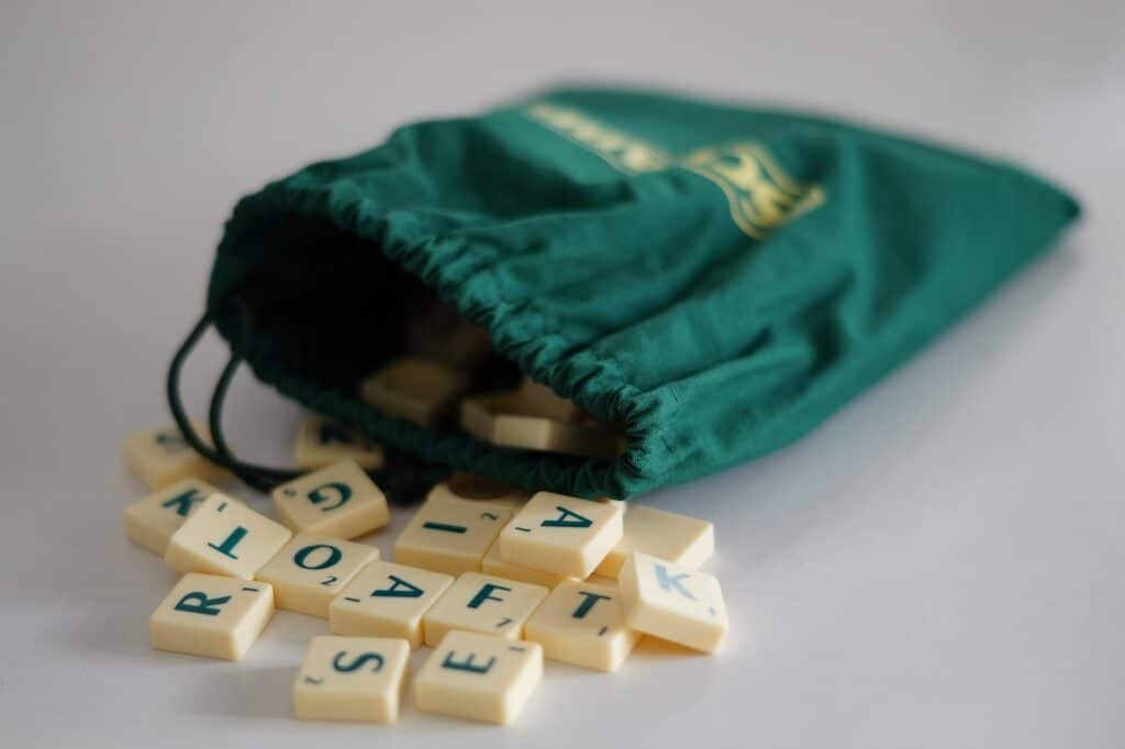 An open bag for holding letter tiles for the word game Scrabble, with tiles spilling out.