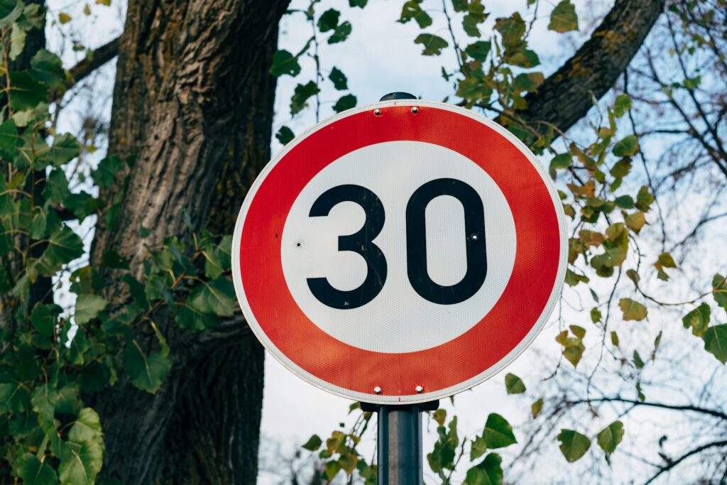 A speed limit road sign. A circular sign with a broad red border around a white circle. The white circle contains the number "30" in large clear black characters.