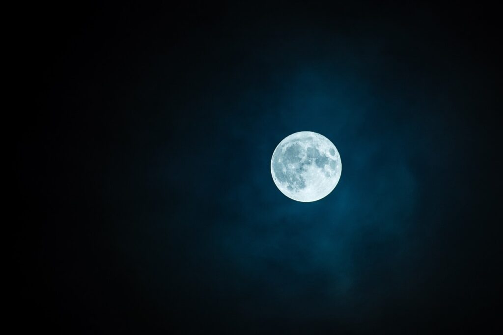 A full Moon in a slightly cloudy night sky