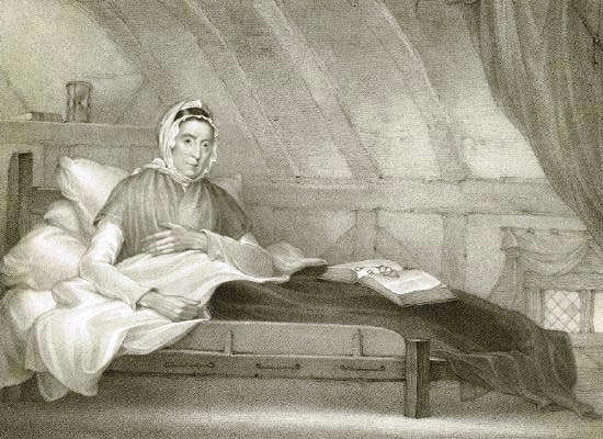 A black and white illustration of a woman sat in bed. She is wearing a shawl and bonnet. A thick book, possibly a Bible, sits open on the bedclothes, with a pair of spectacles resting on top of it.