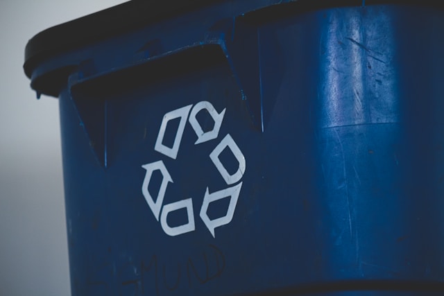 A dark bin, prominently marked with a "Recycling" symbol of three arrows in a circle.