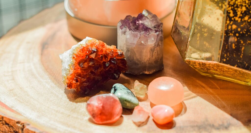 An assortment of crystals and a 'Himalayan salt lamp' stand on a wooden table, made of a section through a whole tree trunk.