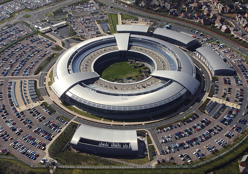 An aerial photograph of a large circular office building surrounded by a car park.
