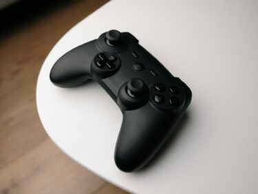 A black video game controller sat on a rounded white table.