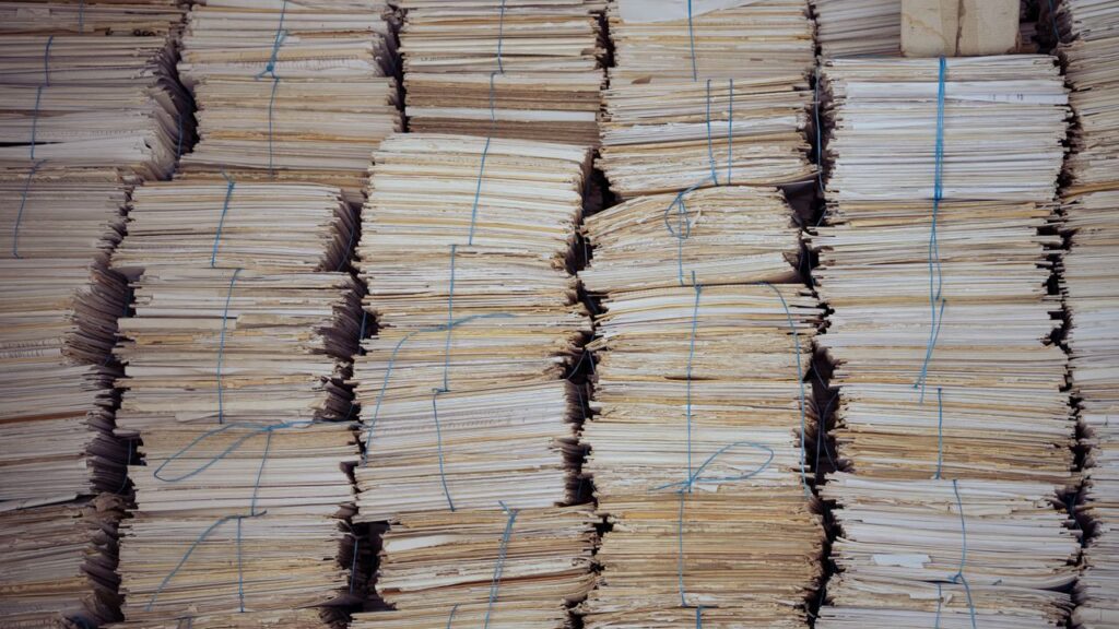 A photograph of several tall stacks of neatly bundled papers, tied up with string.